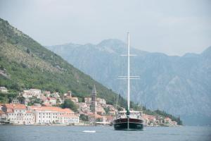 a sail boat in the water in front of a town at Traditional Sailing Yacht in Tivat