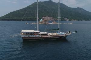 a boat in the water with a mountain in the background at Traditional Sailing Yacht in Tivat