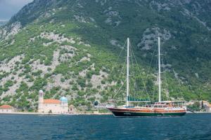 a boat sitting in the water next to a mountain at Traditional Sailing Yacht in Tivat
