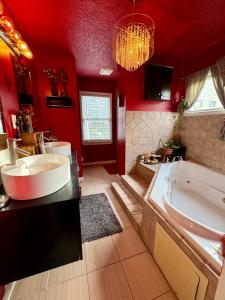 ein Badezimmer mit zwei Waschbecken, einer Badewanne und roten Wänden in der Unterkunft African Zen Oasis in Atlanta