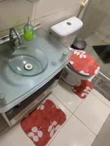 ein Badezimmer mit einem Waschbecken und einem WC mit roten Teppichen in der Unterkunft Quarto privativo Caruaru fácil acesso para o pátio de eventos e feira da sulanca in Caruaru