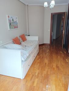 a bedroom with a white bed and a wooden floor at Centro-GASCONA con terraza, garaje y wifi gratuito in Oviedo