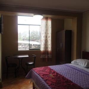 a bedroom with a bed and a table and a window at Gran Hostal Los Pinos in Cajamarca