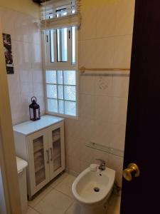 baño con lavabo y aseo y ventana en casa na Torre, en Machico