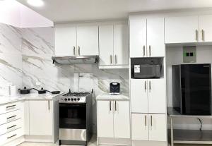 una cocina con armarios blancos y electrodomésticos negros en Casa de Madera y Mármol en Ambato