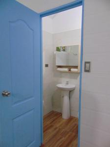 a bathroom with a sink and a blue door at Hostal Suna Vito in Puerto Asís