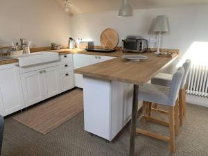 a kitchen with white cabinets and a wooden counter top at Guest Homes - The Teme Loft in Stockton on Teme