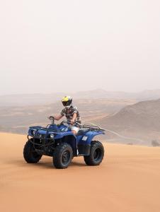 Traditional Riad Merzouga Dunes في مرزوقة: شخص يركب دراجة رباعية في الصحراء