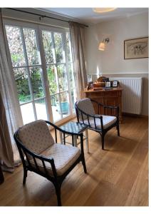 ein Wohnzimmer mit 2 Stühlen, einem Tisch und einem Schreibtisch in der Unterkunft Eine gemütliche Ferienwohnung mit Garten in Bad Karlshafen