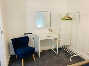 einen Schreibtisch mit einem blauen Stuhl und einem Spiegel in der Unterkunft Captain's Keep - Brixham in Brixham