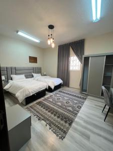 1 dormitorio con 2 camas y alfombra en فيلا السلطان villa alsoltan, en Al Ula