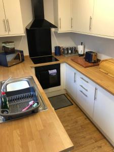 une cuisine avec des armoires blanches et un comptoir dans l'établissement Sleeps 10 5 bedroom town house 3 miles from Zip World, à Blaenau Ffestiniog