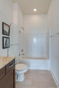 y baño blanco con aseo y ducha. en LOFTS AT 30TH - MODERN LOFT - MINS TO BROADWAY, en Nashville