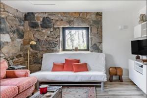 - un salon avec un canapé blanc et un mur en pierre dans l'établissement Studio Guest Suite in Forest Cottage, à Tryon