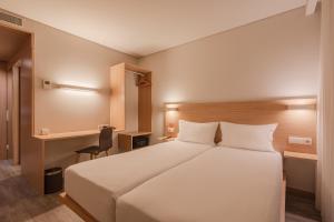 ポルトにあるムーヴ ホテル ポルト ノルテのベッドルーム(白い大型ベッド1台、デスク付)