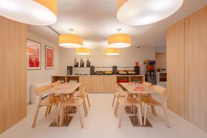 a kitchen and dining room with wooden tables and chairs at Moov Hotel Porto Norte in Porto