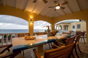 een eetkamer met een tafel en stoelen en de oceaan bij Pelikaan Sunset:A Villa With Stunning Ocean Views in Koolbaai
