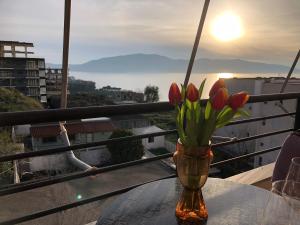 a vase with flowers on a table on a balcony at Jon’s View Home in Vlorë