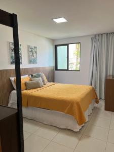 um quarto com uma cama com um cobertor amarelo em Carneiros Beach Resort - Flat 111-D em Praia dos Carneiros