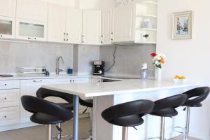 a kitchen with white cabinets and black bar stools at Trebinje Lux Apartment in Trebinje