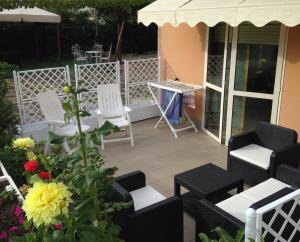 a patio with white chairs and a table and flowers at Residence Regni in Senigallia +18 photos