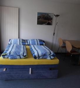 a bed with blue and white pillows in a room at Studio Friedegg in Wildhaus