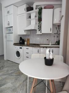 cocina blanca con mesa blanca y armarios blancos en Apartamentos home Chipiona en Chipiona