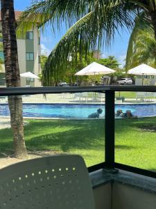 uma vista para a piscina a partir de uma varanda com uma cadeira em Carneiros Beach Resort - Flat 111-D em Praia dos Carneiros
