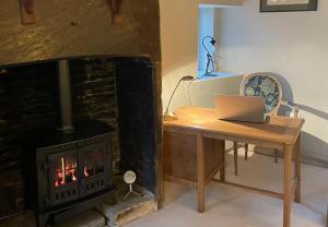 a room with a fireplace and a desk with a laptop at The Therapy Rooms Holmfirth Holiday Let in Holmfirth