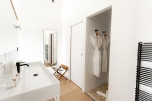 een witte badkamer met een wastafel en een spiegel bij Mas de la Fouque - Hôtel & Spa in Saintes-Maries-de-la-Mer