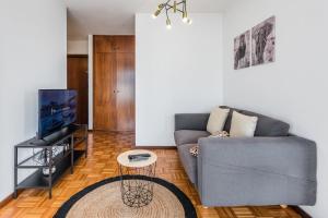 a living room with a gray couch and a tv at GuestReady - One happy stay in Foz do Douro in Porto