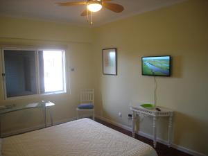 um quarto com uma cama e uma televisão na parede em Shearwaternest Apartment AL em Funchal