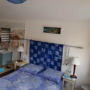 sypialnia z niebieskim łóżkiem i niebieską i białą pościelą w obiekcie LE jardin w mieście Coudeville