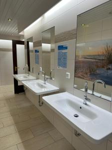 ein Badezimmer mit zwei Waschbecken und zwei Spiegeln in der Unterkunft Wohnwagen auf dem Wulfenerhals in Fehmarn