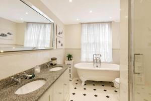 a bathroom with a tub and a sink and a bath tub at Secluded Royal Ground Residence Sleeps 4 in London