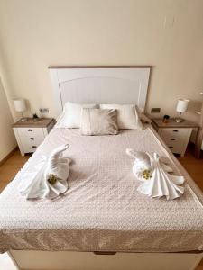 1 Schlafzimmer mit einem Bett mit weißer Bettwäsche und 2 weißen Handtüchern in der Unterkunft Candela Beach Luxury Apartament in Motril