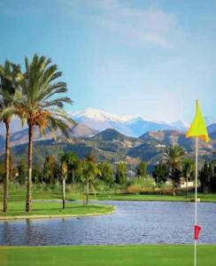 einen Golfplatz mit einem Teich, Palmen und Bergen in der Unterkunft Candela Beach Luxury Apartament in Motril