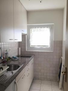 une cuisine blanche avec un évier et une fenêtre dans l'établissement Appartamento Doris, à Locarno