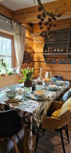 a dining room with a table with plates and dishes on it at Chata Natura in Muszyna