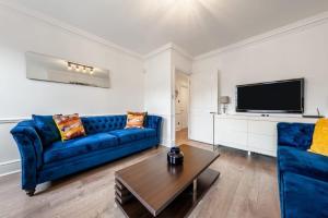 sala de estar con sofá azul y TV en Mayfair Residences en Londres