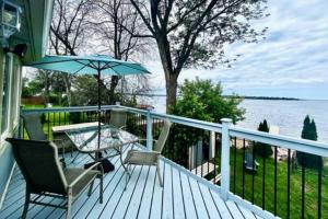 a porch with a table and chairs and an umbrella at Cozy Waterfront Cottage in Victoria Harbour in Victoria Harbour