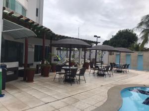 eine Terrasse mit Tischen, Stühlen und Sonnenschirmen neben einem Pool in der Unterkunft Ap Estilo & conforto vista piscinas in Caldas Novas