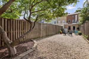 einen Zaun mit einem Baum und Stühlen im Hof in der Unterkunft Cooper House Fells Point Large Fenced In Yard in Baltimore