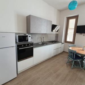 a kitchen with white appliances and a wooden table at ILLY HOUSE in Alghero