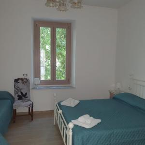 a bedroom with a bed and a window and a chair at ILLY HOUSE in Alghero