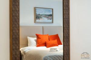 a mirror reflection of a bed with orange pillows at Royal 4 Bedroom Apartment in Mayfair in London