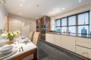 a kitchen with white cabinets and a table and chairs at Royal 4 Bedroom Apartment in Mayfair in London