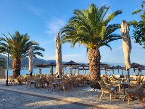 a patio with tables and chairs and palm trees at Blue Sea Horizon in Iraklitsa