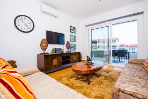 Una sala de estar con un sofá y un reloj en la pared. en Santino Apartment, en Caniço