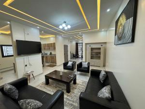 sala de estar con 2 sofás negros y TV en Complexe La Perfection en Nuakchot